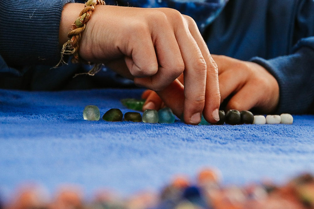 child working with glass beads in Sijwa project